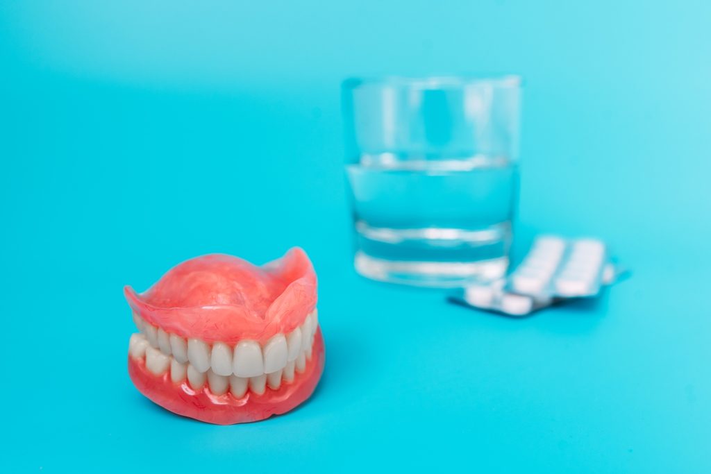 A prosthesis and a glass with a solution. Dental prosthesis care