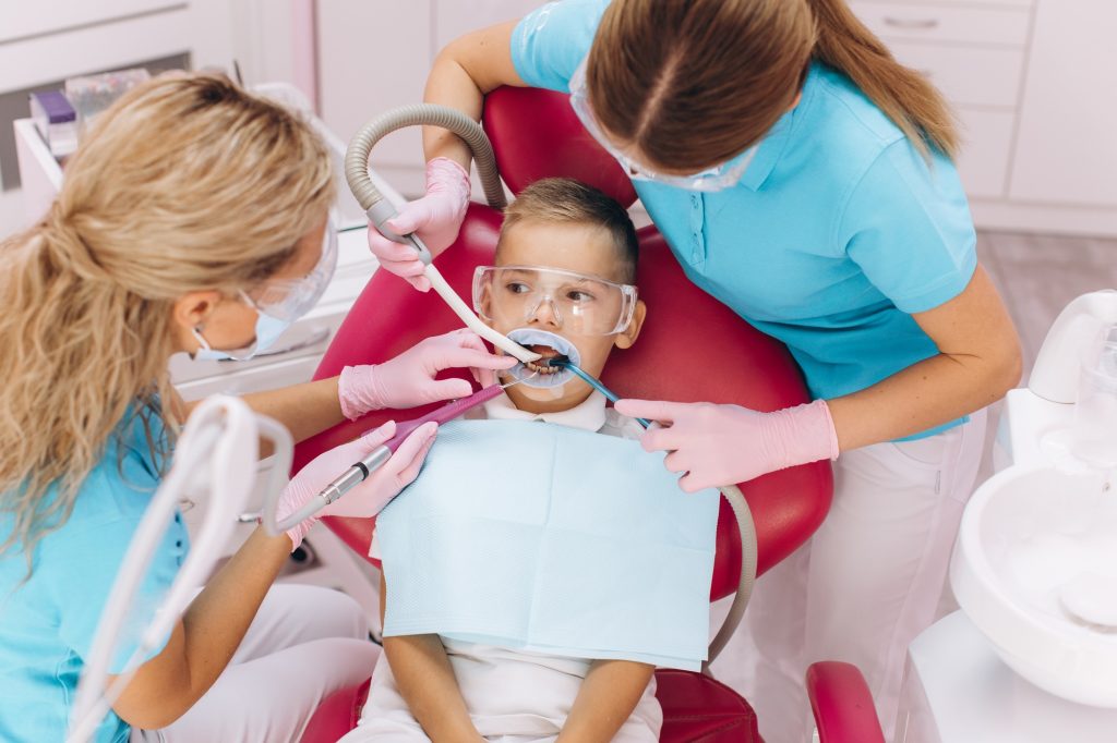 Female dentist treats boy's teeth in dental clinic